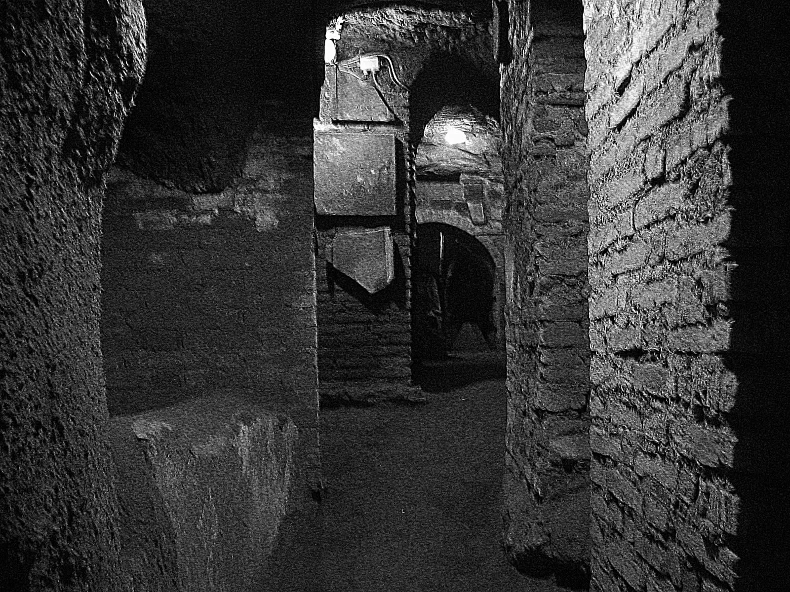 Une galerie voûtée des catacombes de Saint-Sébastien à Rome, aux parois creusées de niches funéraires fermées par des dalles de pierre