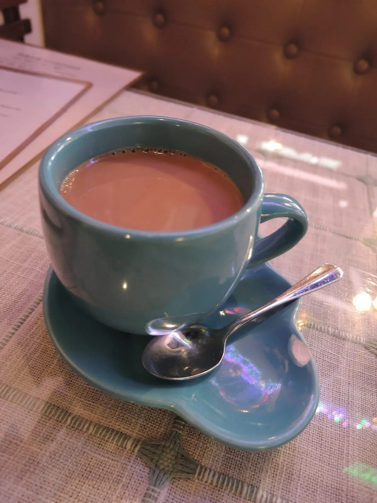 Tasse de chocolat chaud à la mousse onctueuse, posée sur sa soucoupe avec une cuillère