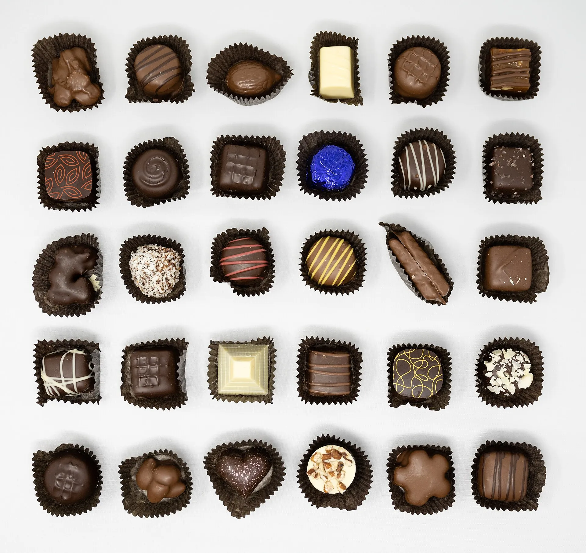 Assortiment de pralines et de chocolats fins, noir, au lait et blanc, présentés dans leurs caissettes