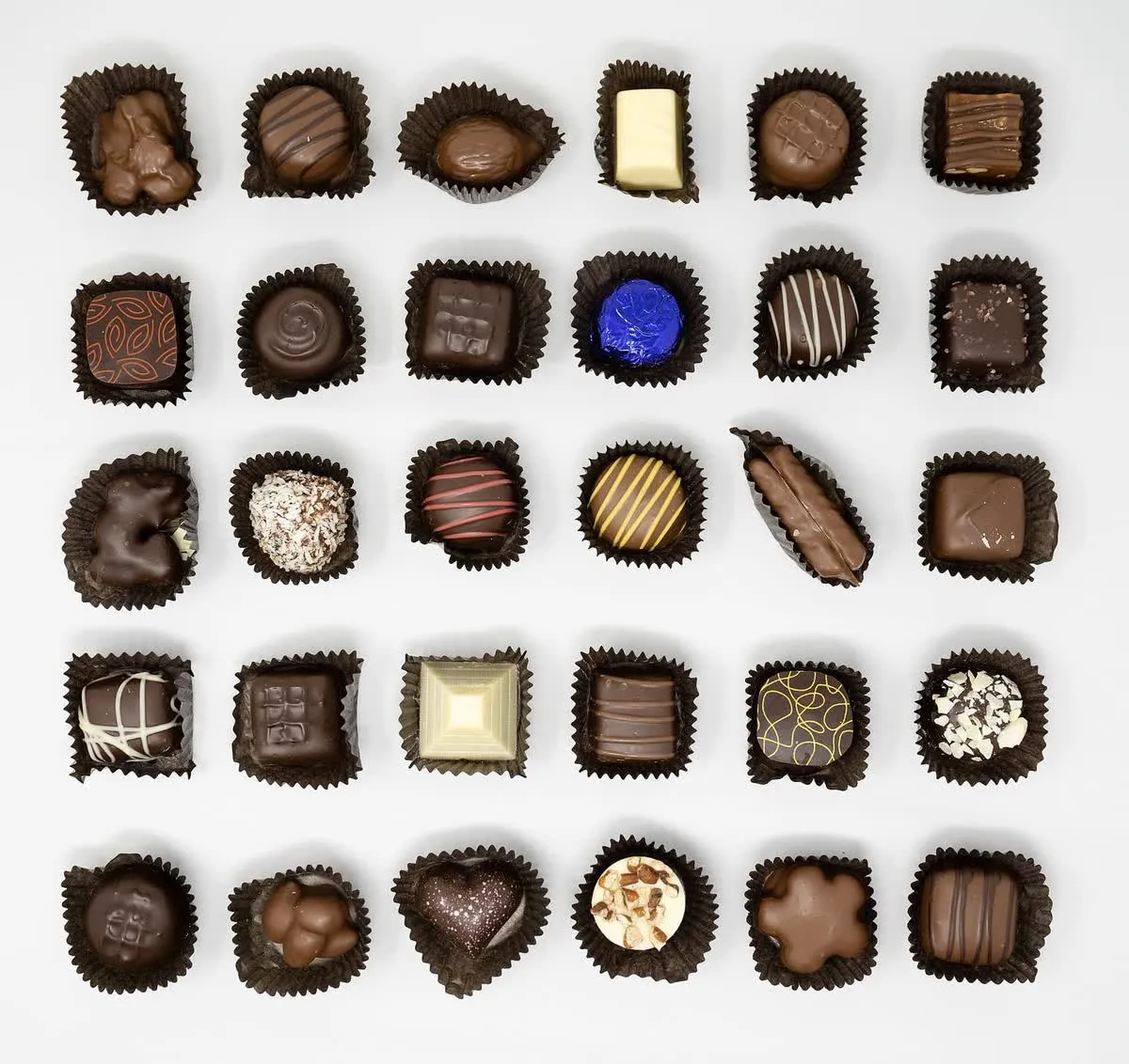 Assortiment de pralines et de chocolats fins, noir, au lait et blanc, présentés dans leurs caissettes