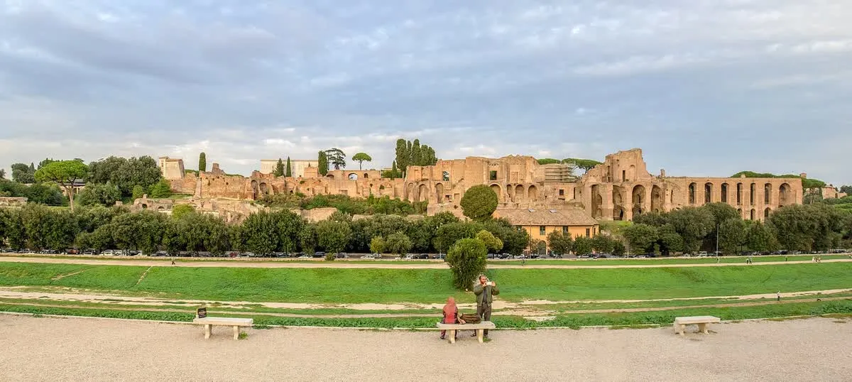 Vue du Circus Maximus à Rome : l'immense esplanade gazonnée de la vallée de la Murcia au premier plan, avec le Palatin et ses ruines en arrière-plan