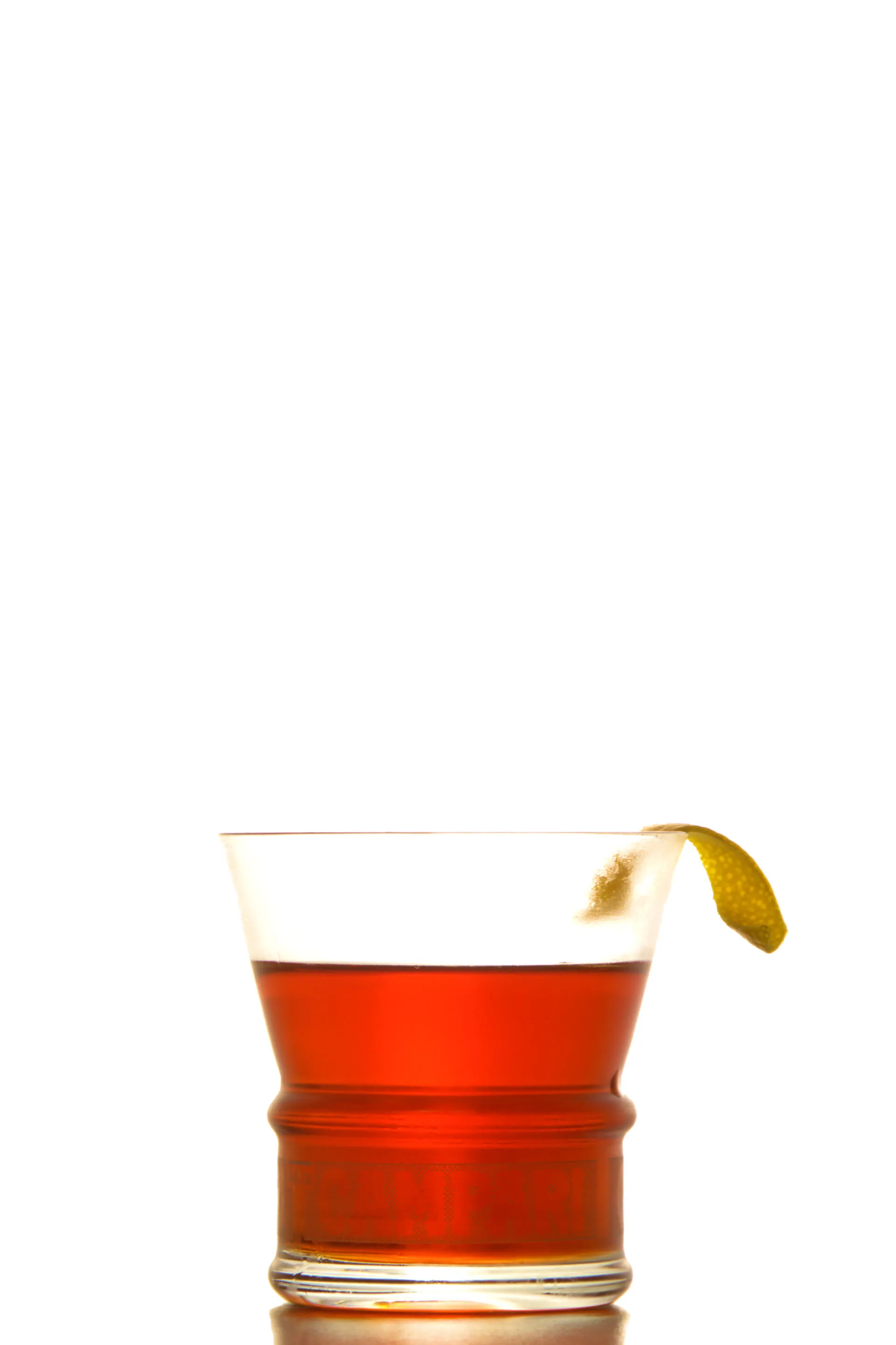 Un cocktail rouge servi dans un verre à fond épais, garni d'un zeste d'agrume, sur fond blanc