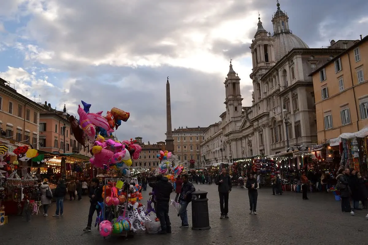 Étals du marché de Noël installés sur la piazza Navona à Rome, avec l'obélisque et les coupoles baroques en arrière-plan