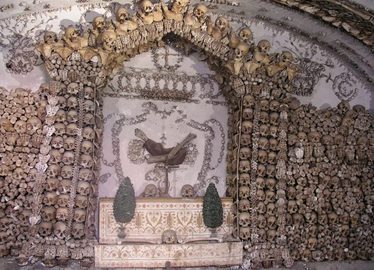 Une chapelle de la crypte des Capucins à Rome, murs tapissés de crânes et arche de vertèbres au-dessus de l'autel