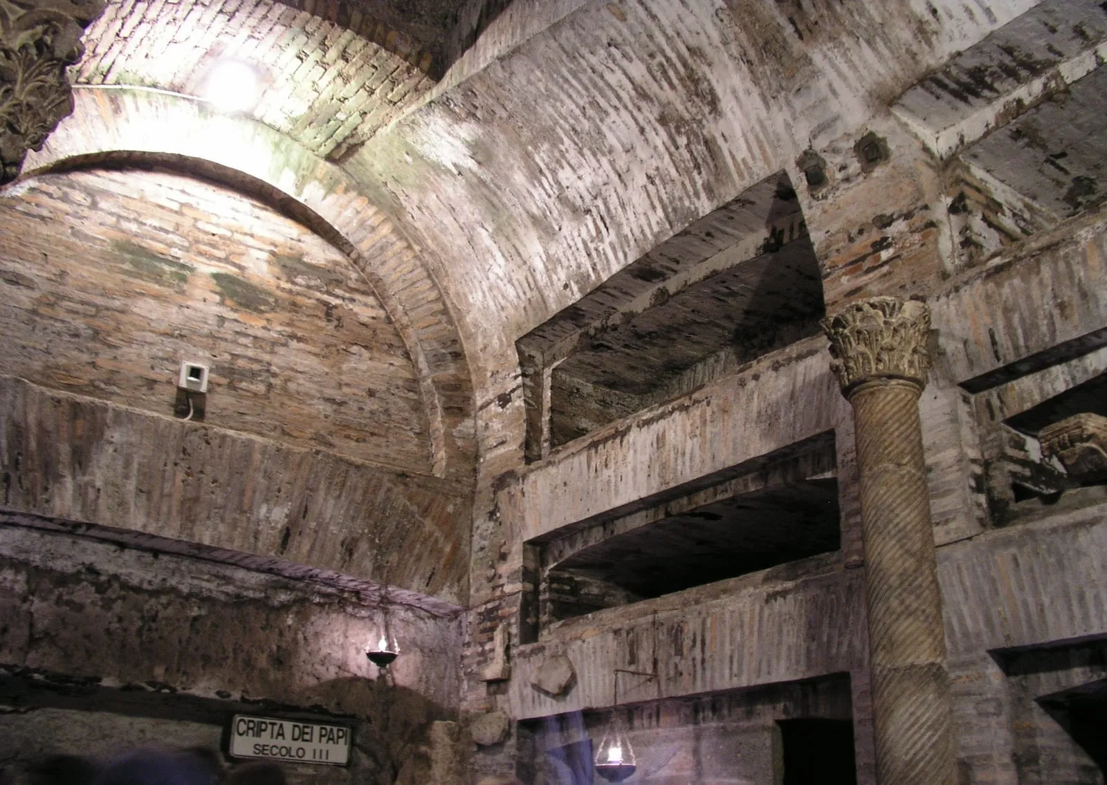 La crypte des Papes dans les catacombes de San Callisto, avec ses tombes en niches voûtées et ses lampes à huile