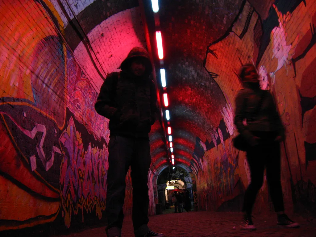 L'androne du centre social Forte Prenestino, passage voûté en brique couvert de graffitis, éclairé pour une soirée