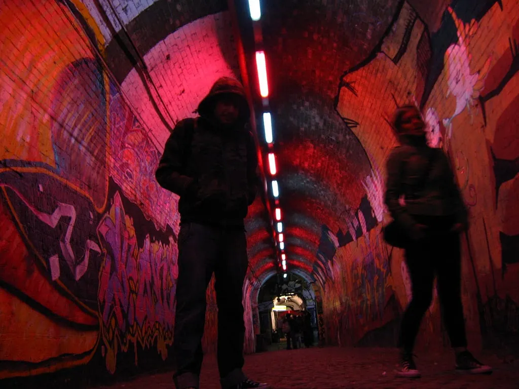L'androne du centre social Forte Prenestino, passage voûté en brique couvert de graffitis, éclairé pour une soirée