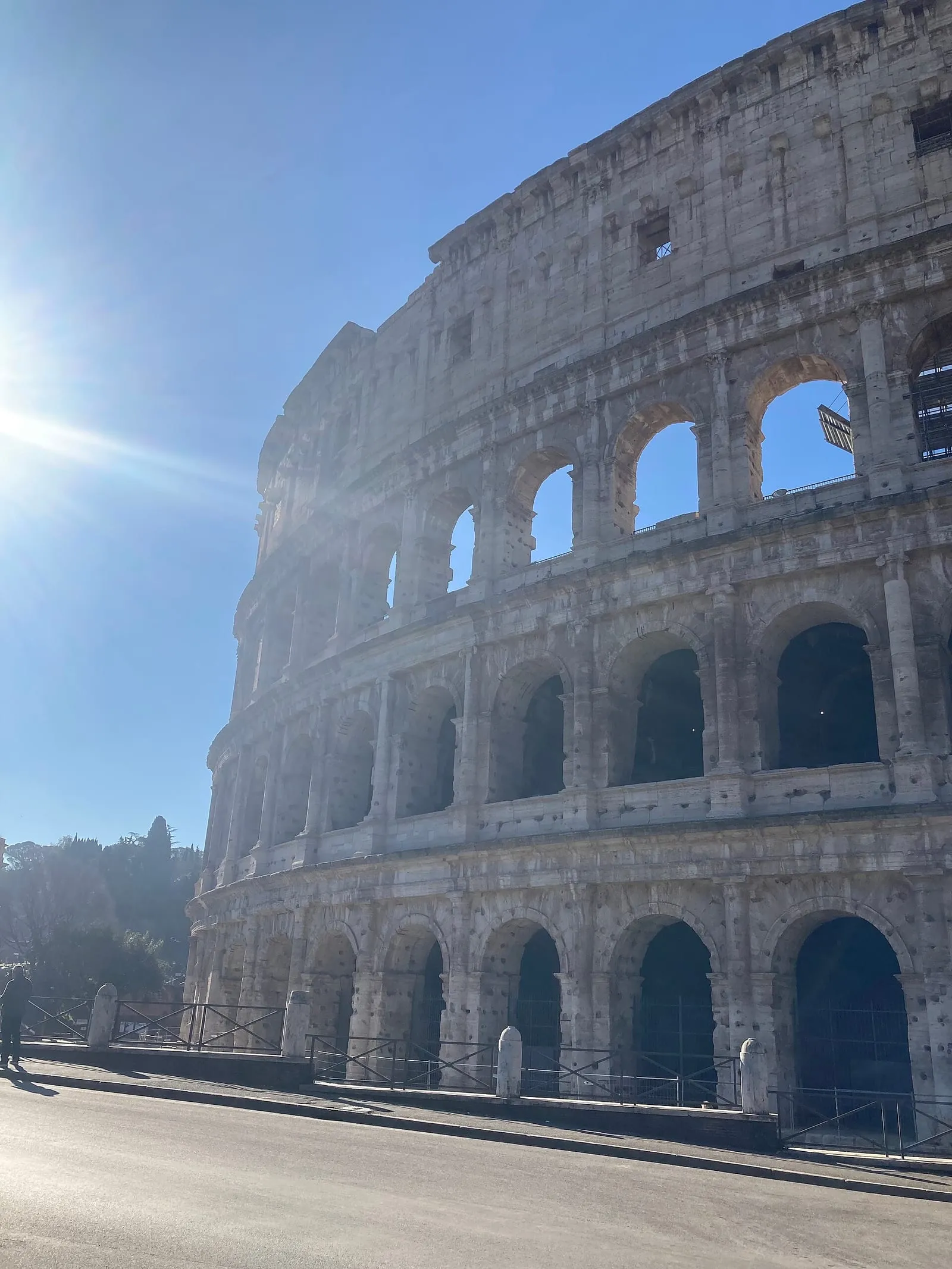 La façade du Colisée en lumière rasante d'hiver, soleil bas et éclatant dans un ciel bleu, rue presque déserte au premier plan