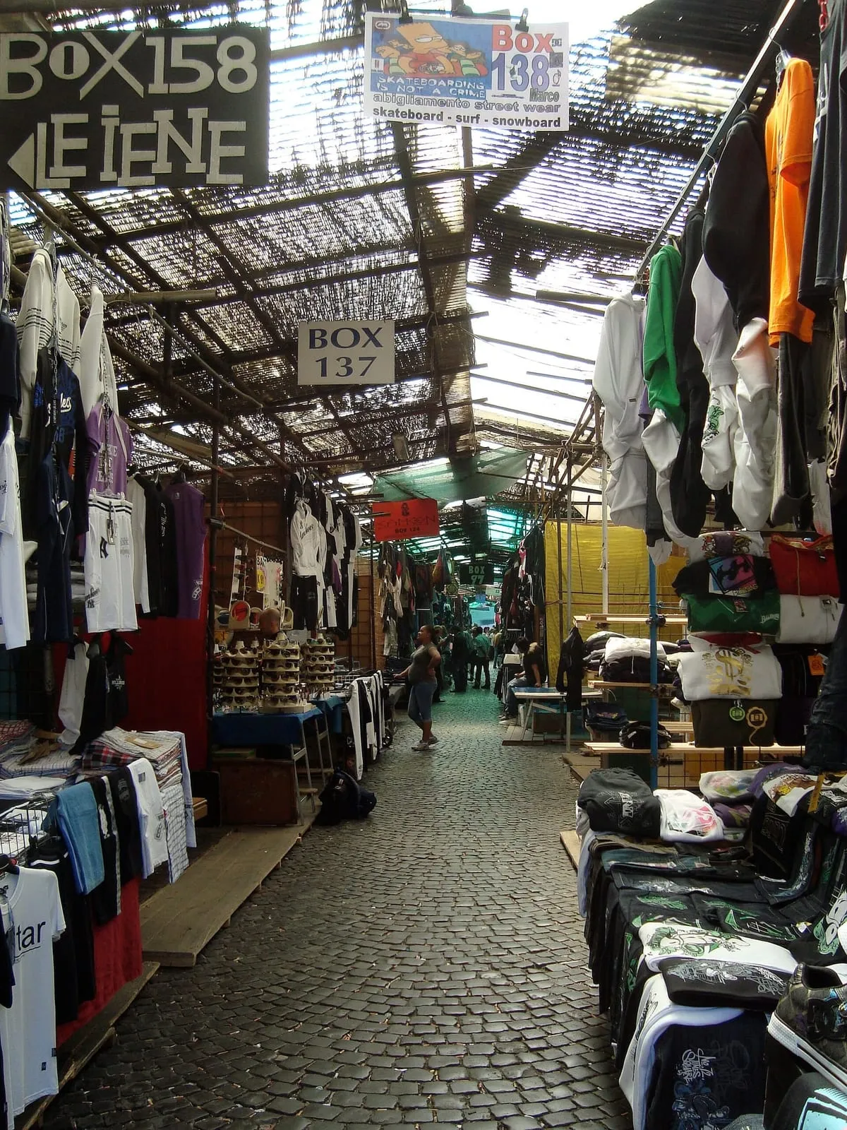 Allée couverte du marché de Via Sannio bordée de portants de vêtements