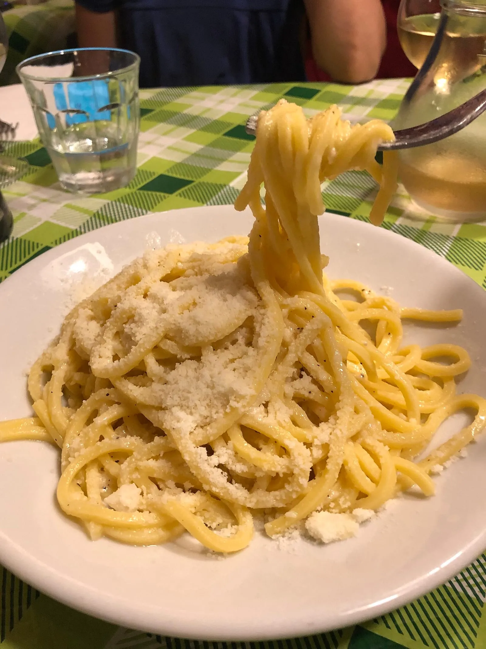 Assiette de tonnarelli cacio e pepe servie dans une trattoria romaine, pâtes fraîches nappées de pecorino et de poivre