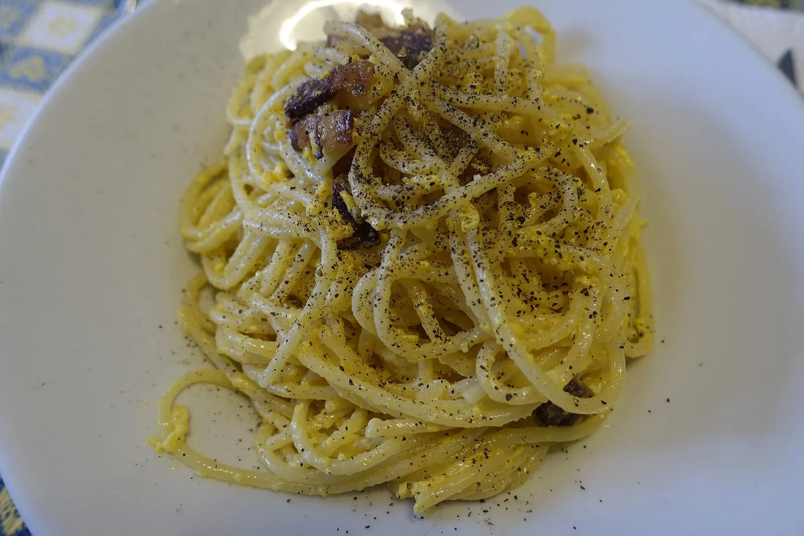 Spaghetti alla carbonara dans une assiette blanche, avec guanciale, jaune d'oeuf et pecorino râpé