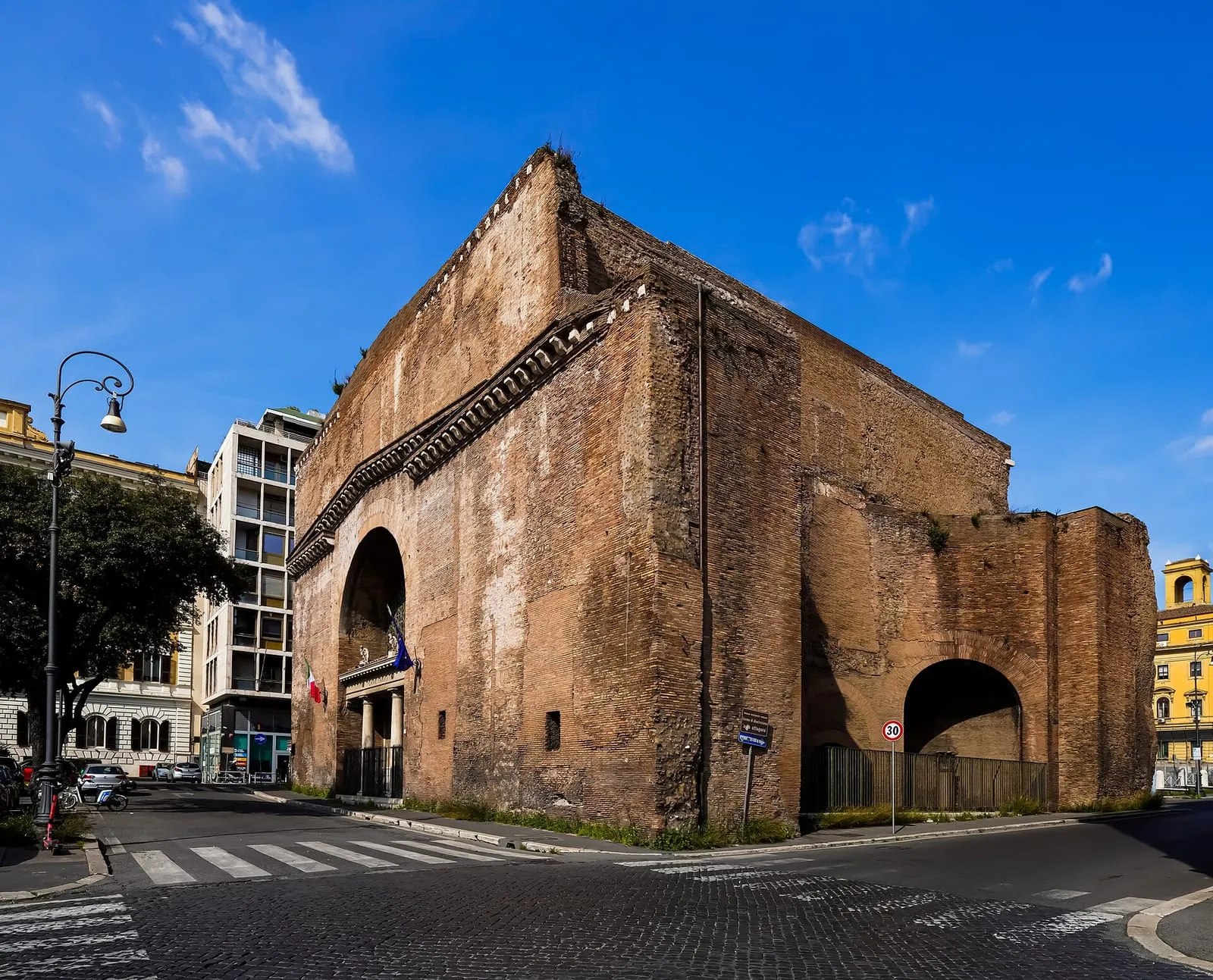 Mur de brique antique de la salle octogonale des thermes de Dioclétien à Rome, ouvert d'une grande arcade, sous un ciel bleu