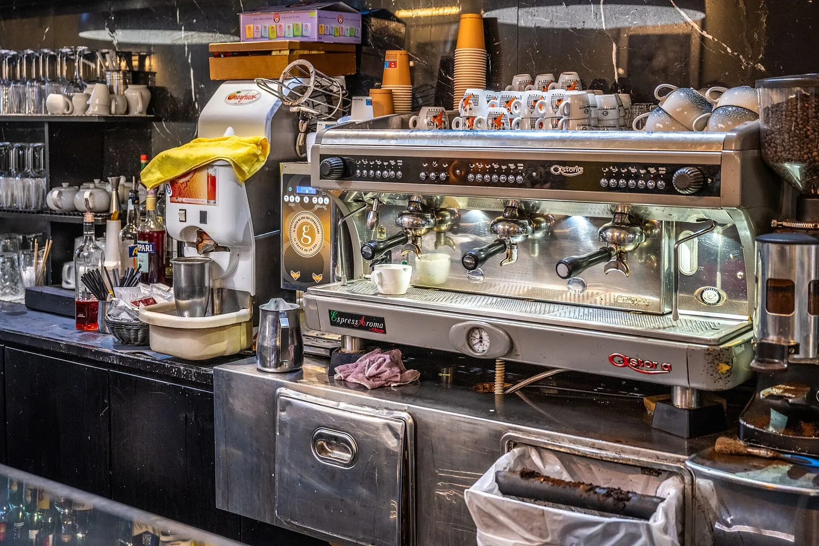 Comptoir d'un bar à café romain, machine à espresso, piles de tasses blanches et gobelets empilés