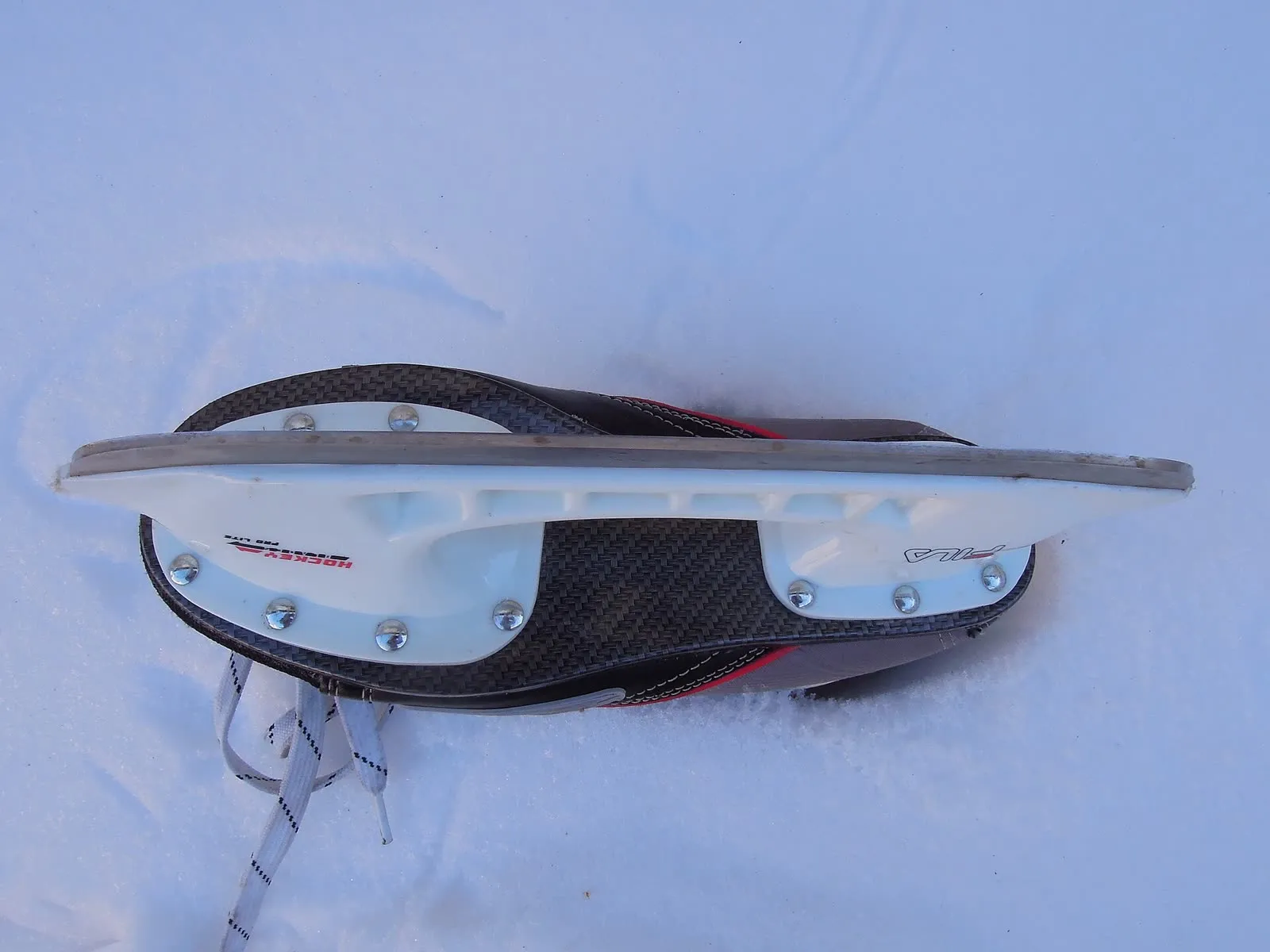 Un patin de glace en gros plan, lame et chaussure, posé dans la neige