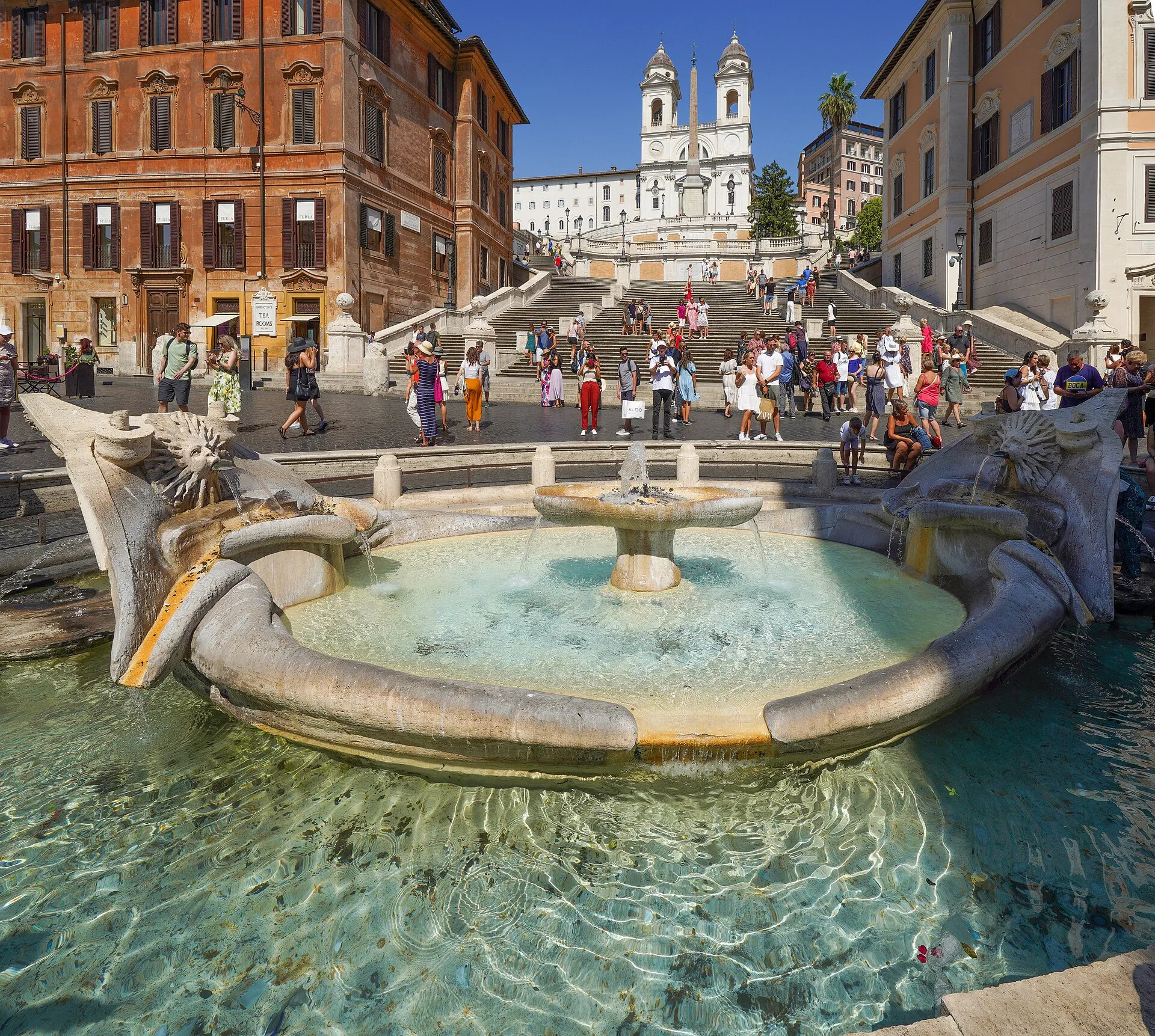La fontaine de la Barcaccia à Rome, barque de pierre à demi immergée, au pied de l'escalier de la Trinité-des-Monts encombré de promeneurs