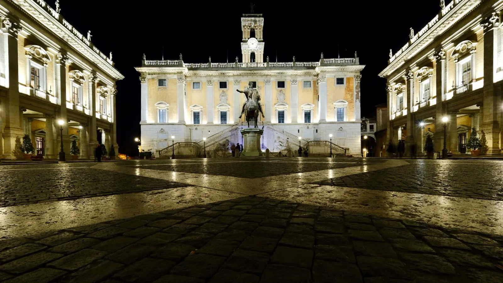 La piazza del Campidoglio de nuit, le palais sénatorial éclairé au fond, la statue équestre de Marc Aurèle au centre et le pavement en étoile au premier plan