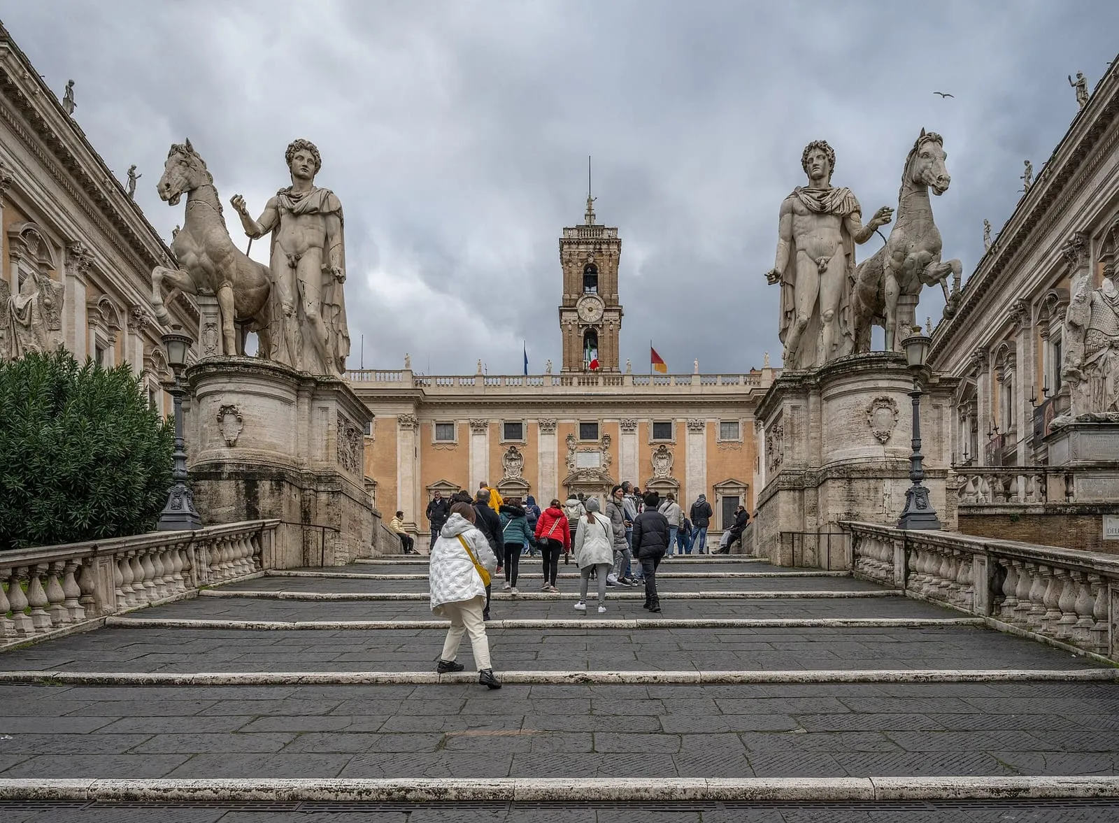 La Cordonata qui monte à la piazza del Campidoglio à Rome, sous un ciel d'hiver gris, avec des visiteurs en manteau