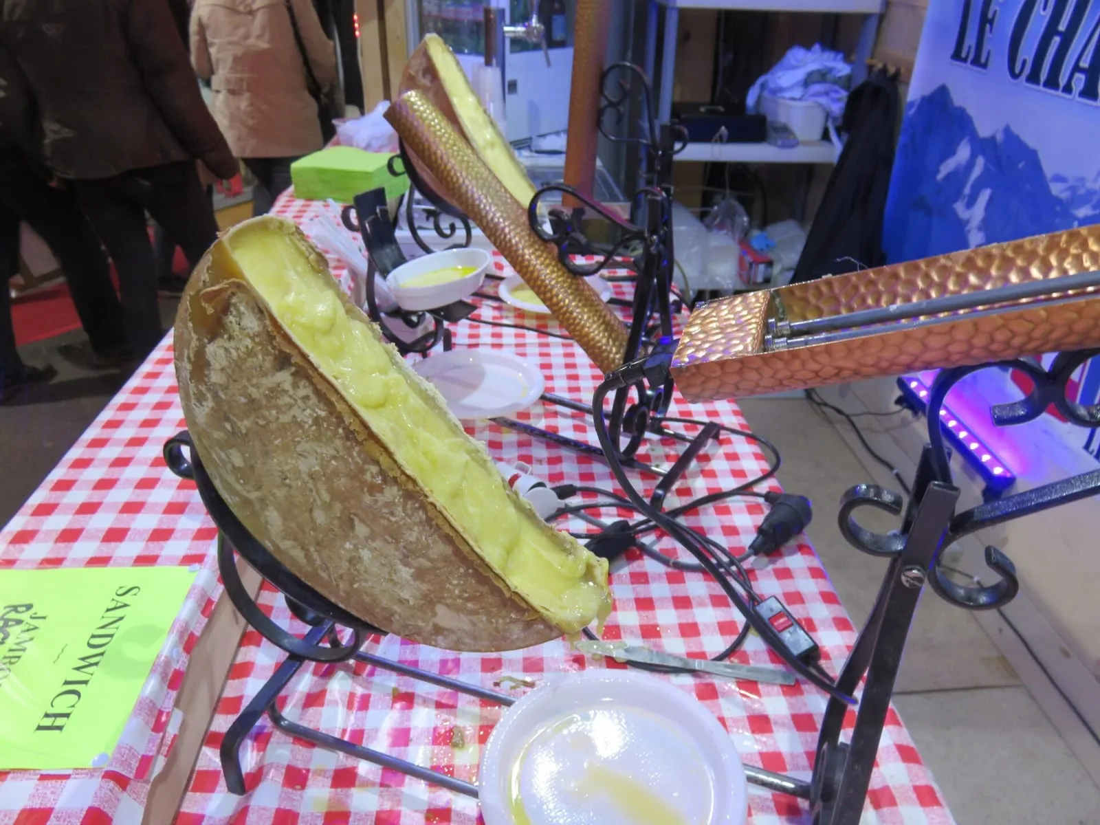 Demi-meule de raclette sous son appareil, fromage fondu raclé sur les pommes de terre