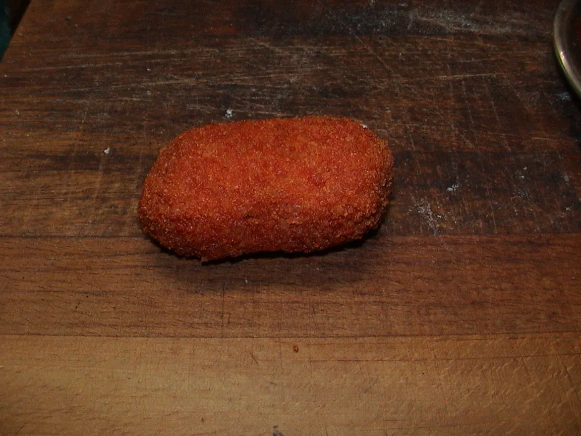 Supplì romain, croquette de riz panée et frite, posé sur une planche en bois