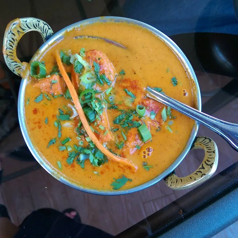 Poulet tikka masala dans un plat métallique, sauce crémeuse à la tomate garnie de coriandre