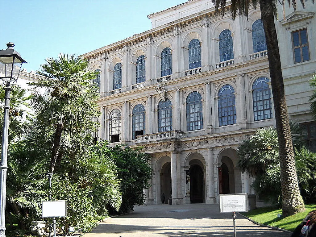 La façade du Palazzo Barberini à Rome, avec son portique en rez-de-chaussée, ses fenêtres à fronton et ses palmiers devant l'entrée