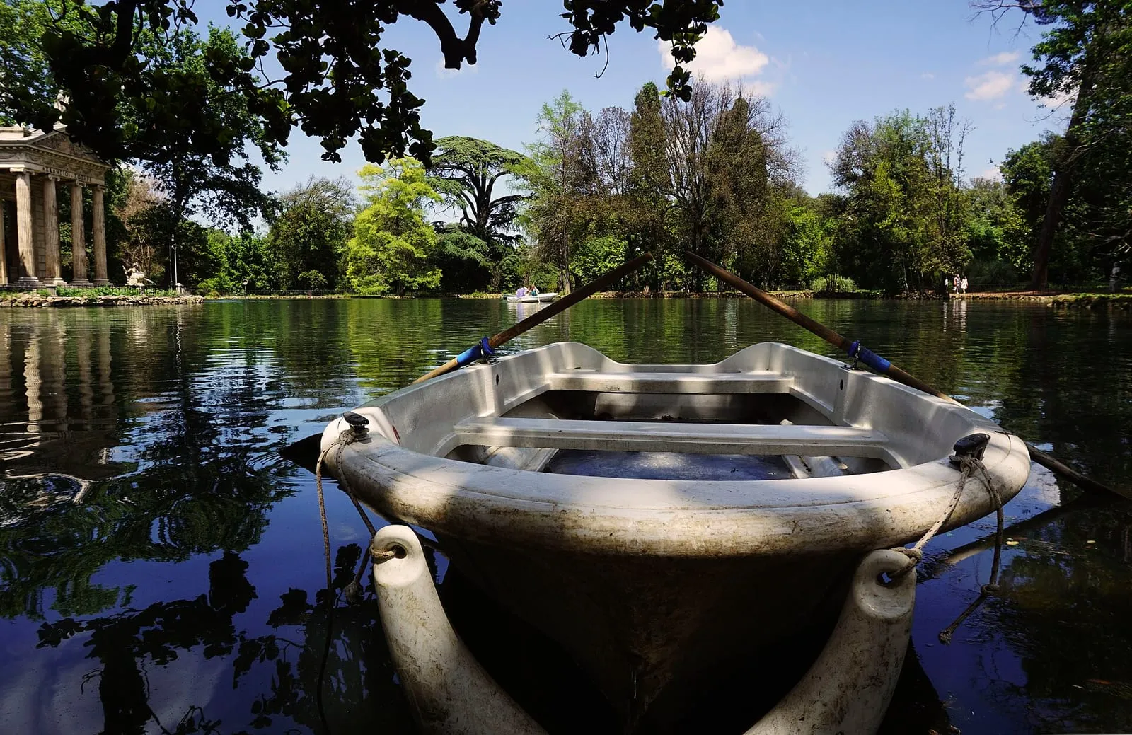 Barque de location amarrée sur le lac du jardin du Lago, à la Villa Borghese, avec la colonnade du temple d'Esculape et les pins à l'arrière-plan