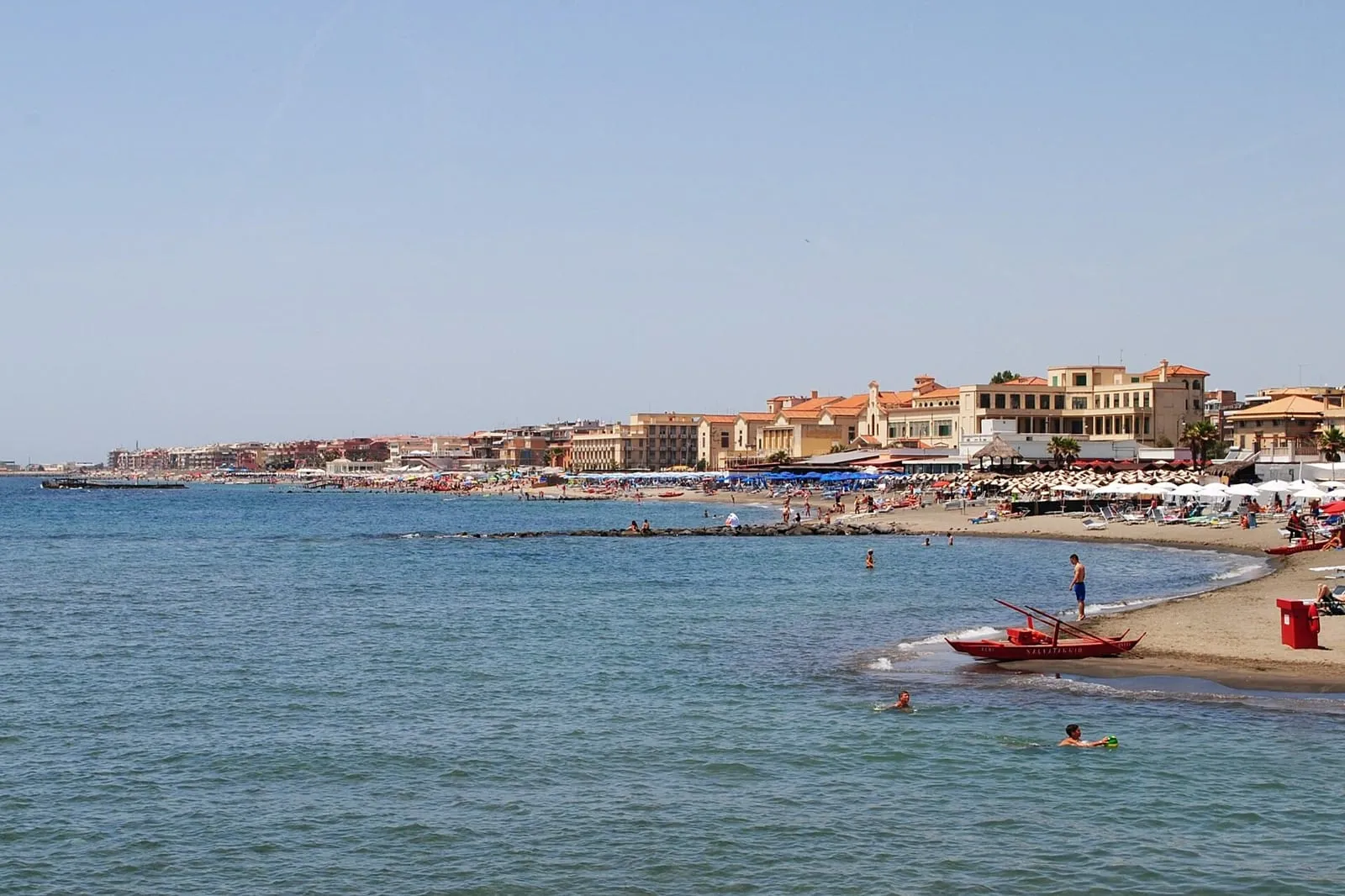 Plage du Lido d'Ostia en été, avec ses rangées de parasols, ses baigneurs et le front de mer en arrière-plan