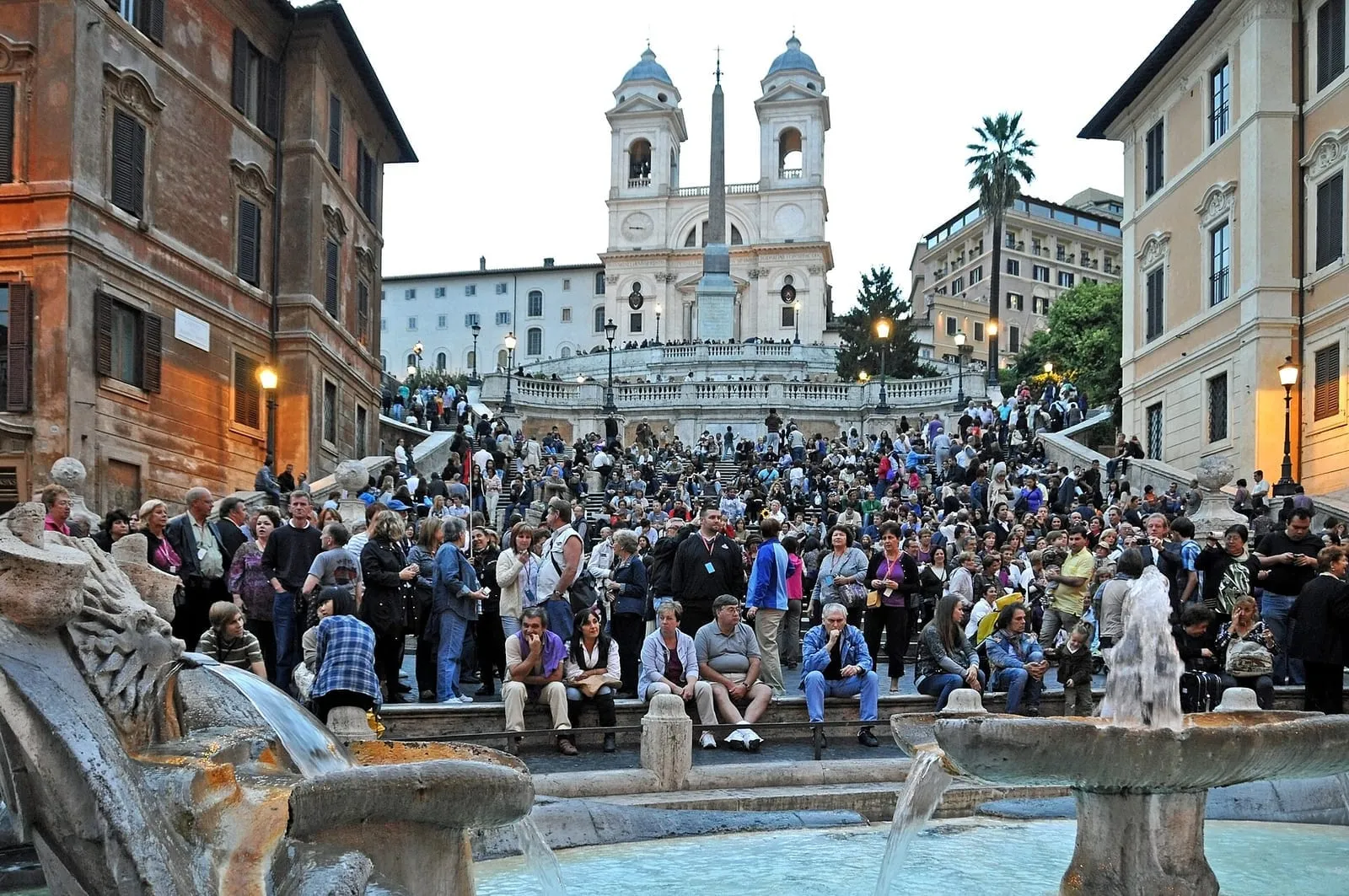 L'escalier de la Trinité-des-Monts à Rome, couvert de visiteurs, surmonté de l'église et de l'obélisque, avec la fontaine de la Barcaccia au premier plan
