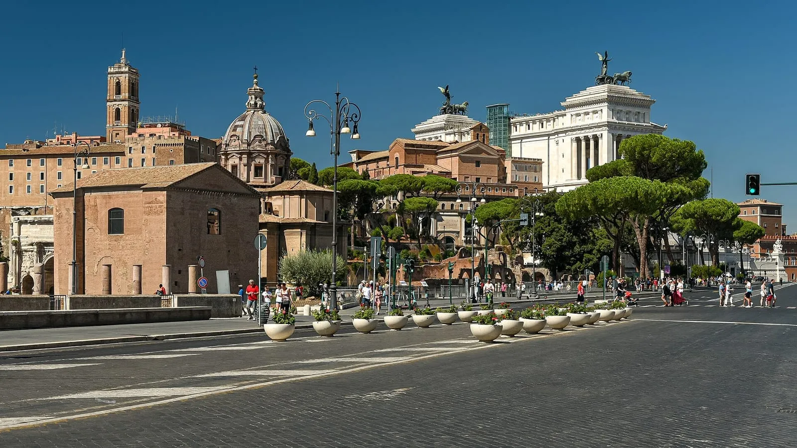 La via dei Fori Imperiali à Rome, large avenue bordée de ruines antiques et de pins parasols, parcourue par des promeneurs