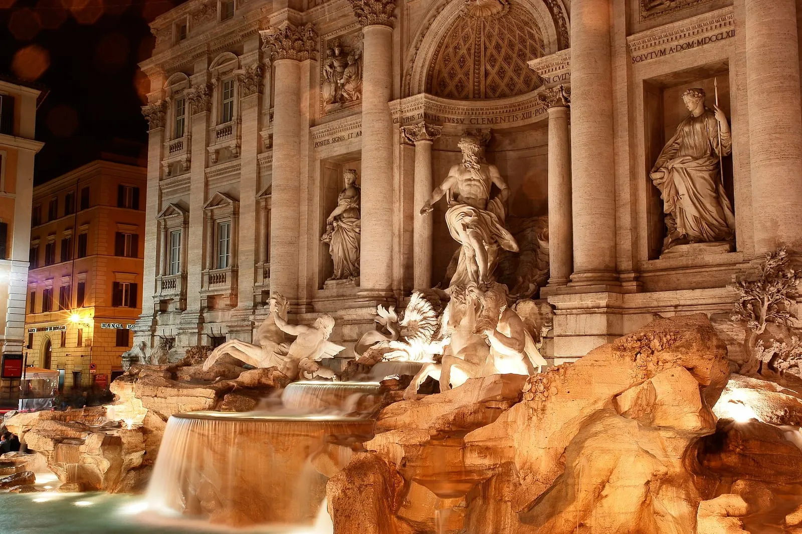 La fontaine de Trevi illuminée de nuit, sa façade baroque éclairée et son bassin rocheux