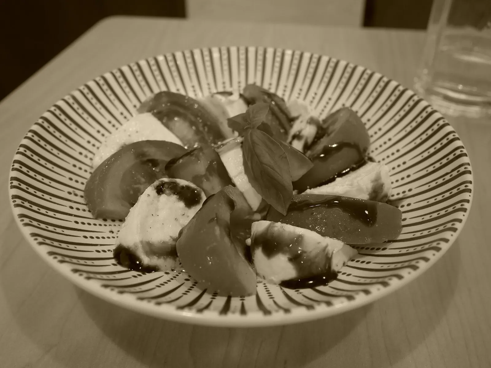 Salade de tomates et mozzarella servie dans un bol brun, posée sur une table