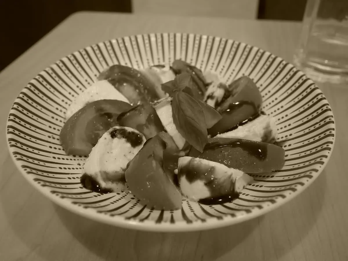 Salade de tomates et mozzarella servie dans un bol brun, posée sur une table