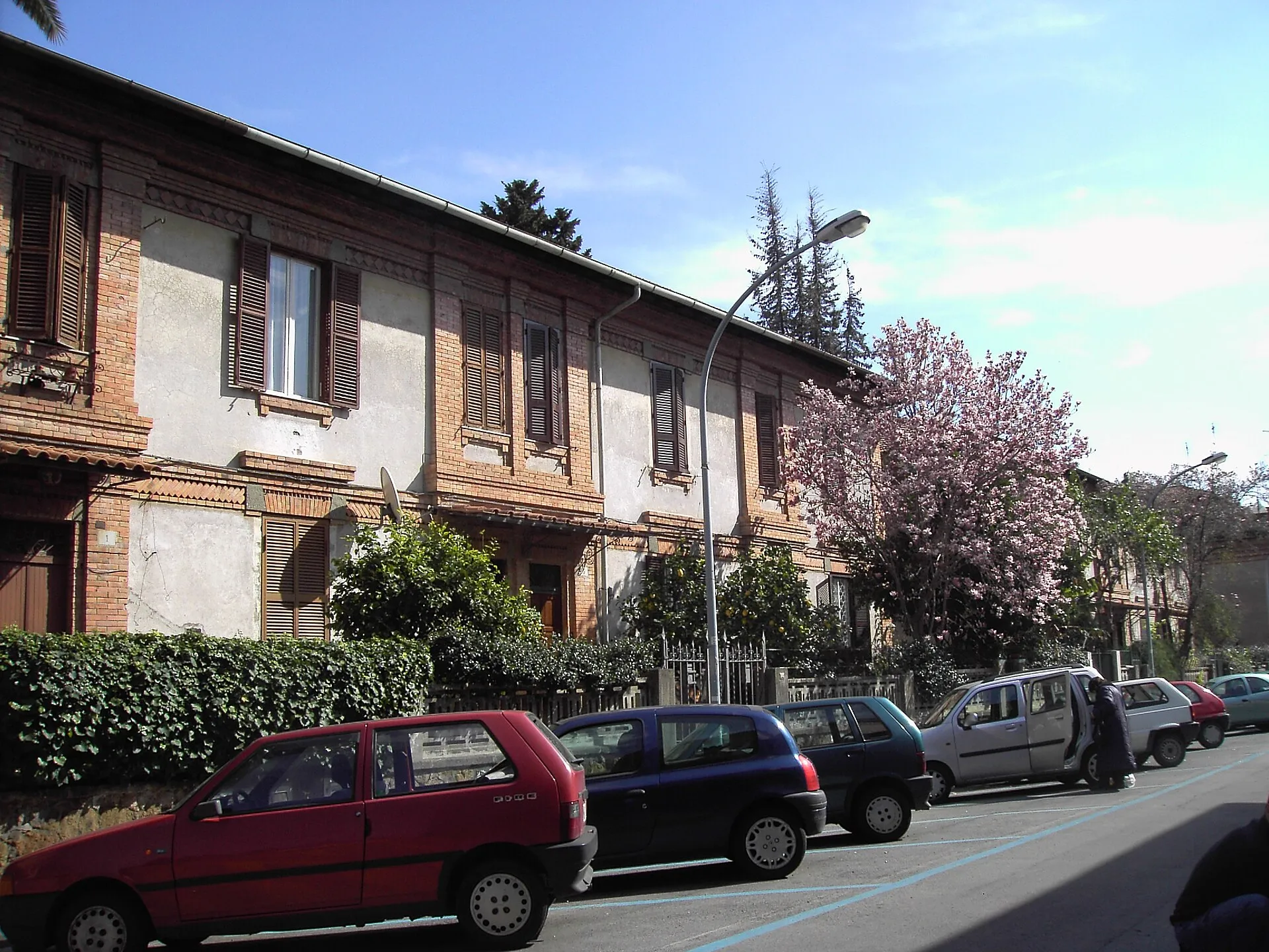 Voitures garées le long du trottoir dans le quartier San Saba, à Rome, devant un immeuble en briques