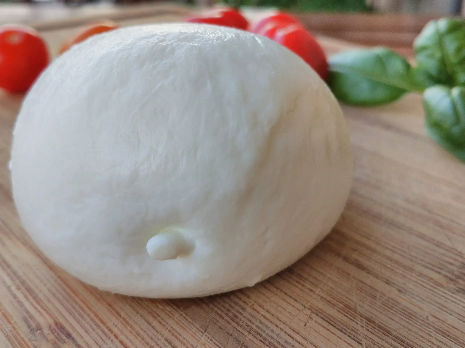 Mozzarella di bufala fraîche sur une planche en bois, avec tomates cerises et basilic